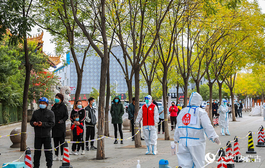 呼和浩特市玉泉區(qū)一處核酸篩查點(diǎn)，黨員志愿者對(duì)核酸采樣通道進(jìn)行消殺。丁根厚攝