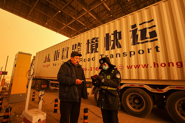 滿洲里邊檢站民警在沙塵天氣下查驗(yàn)通關(guān)貨車證件。安吉拉攝