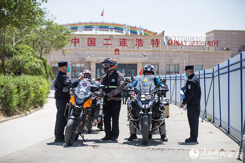二連出入境邊防檢查站執(zhí)勤民警查驗自駕旅游團成員通關(guān)證件。胡富國攝