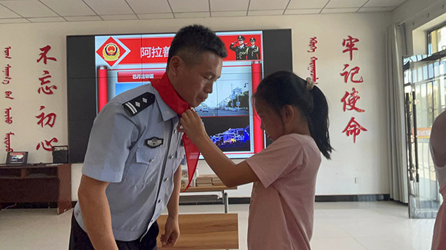 小朋友為警察叔叔佩戴紅領(lǐng)巾。