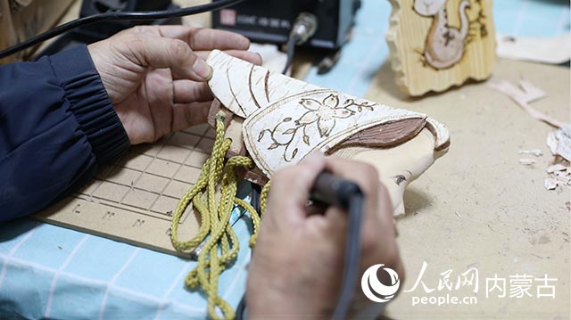 蘇殿政對(duì)朽木粘畫(huà)進(jìn)行燙畫(huà)工藝處理。孟佳澍攝