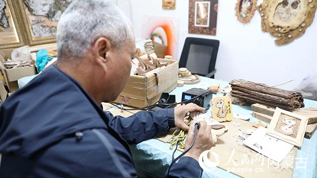 蘇殿政對(duì)朽木粘畫(huà)進(jìn)行燙畫(huà)工藝處理。
