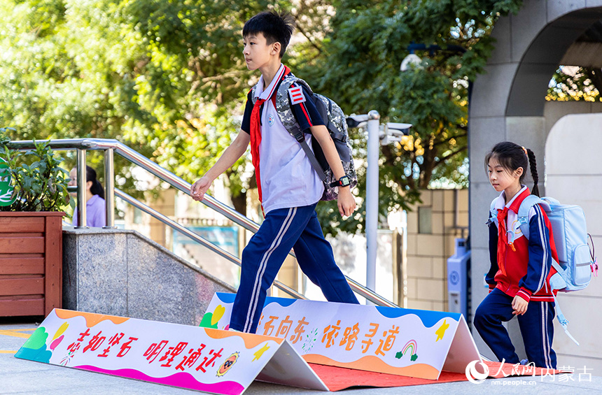 呼和浩特市玉泉區(qū)石東路小學學生跨越勵志牌進入校園。丁根厚攝