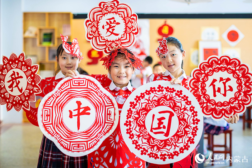 呼和浩特市玉泉區(qū)恒昌店巷小學(xué)五里營(yíng)校區(qū)的學(xué)生在展示“我愛(ài)你中國(guó)”剪紙作品。丁根厚攝