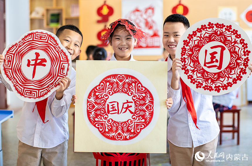 呼和浩特市玉泉區(qū)恒昌店巷小學五里營校區(qū)的學生在展示迎國慶主題剪紙作品。丁根厚攝
