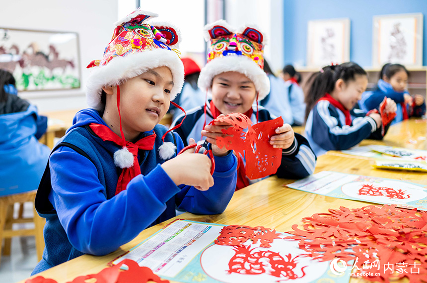 呼和浩特市玉泉區(qū)南柴火市街小學(xué)學(xué)生在制作窗花剪紙作品。丁根厚攝