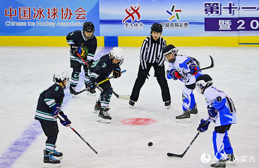 12月19日，內(nèi)蒙古冰雪運動學校少年冰球隊球員（黑色運動服）與陳巴爾虎旗民族小學球員在少年組比賽中爭球。王正攝