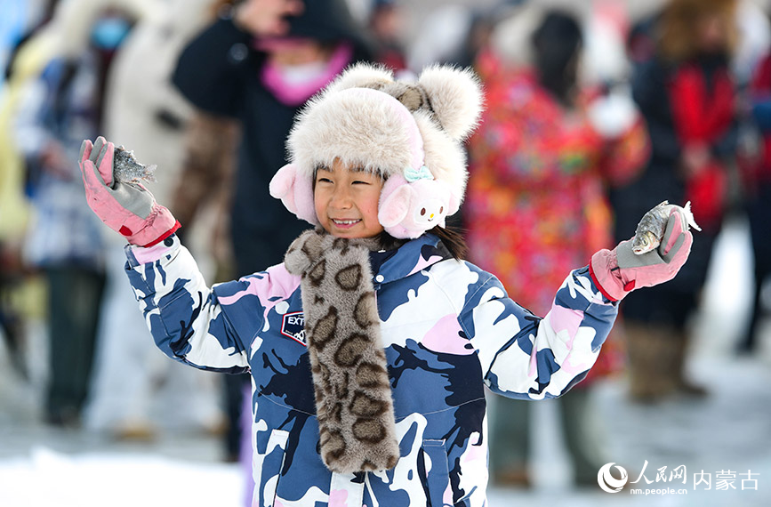 2024年12月22日，小朋友在黑山頭口岸景區(qū)冰釣體驗(yàn)區(qū)展示捕獲的白魚。王正攝