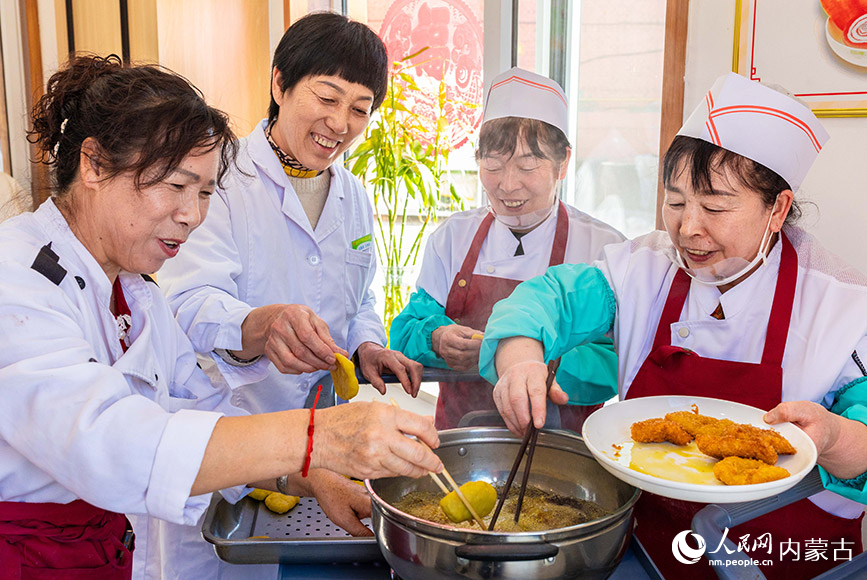 1月20日，工作人員在呼和浩特市玉泉區(qū)民政局迎新春主題活動(dòng)現(xiàn)場(chǎng)為老人們制作油炸糕。丁根厚攝